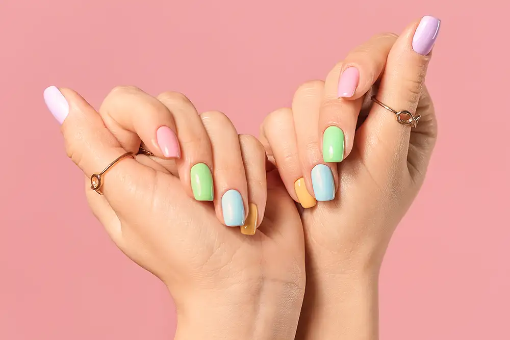 Hände einer jungen Frau mit schöner Maniküre auf farbigem Hintergrund